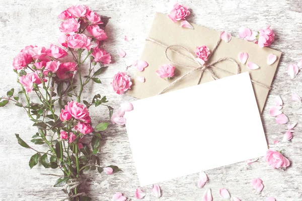 Ramo de rosas tiernas con una tarjeta de felicitación en blanco y sobre — Foto de Stock