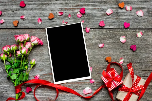 Buket pembe güller, hediye kutuları, ahşap kalpleri ile boş fotoğraf çerçevesi — Stok fotoğraf