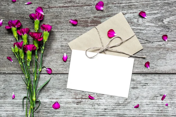 Tarjeta de felicitación blanca en blanco y sobre con flores de clavel púrpura — Foto de Stock