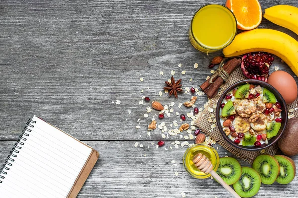 Café da manhã saudável com aveia de frutas, frutas frescas, mel, ovo e suco de laranja com livro de receitas — Fotografia de Stock