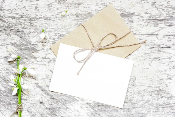 Boş beyaz tebrik kartı ve zarf kardelen çiçekli — Stok fotoğraf