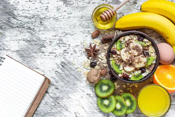 Café da manhã saudável com aveia de frutas e caderno em branco — Fotografia de Stock