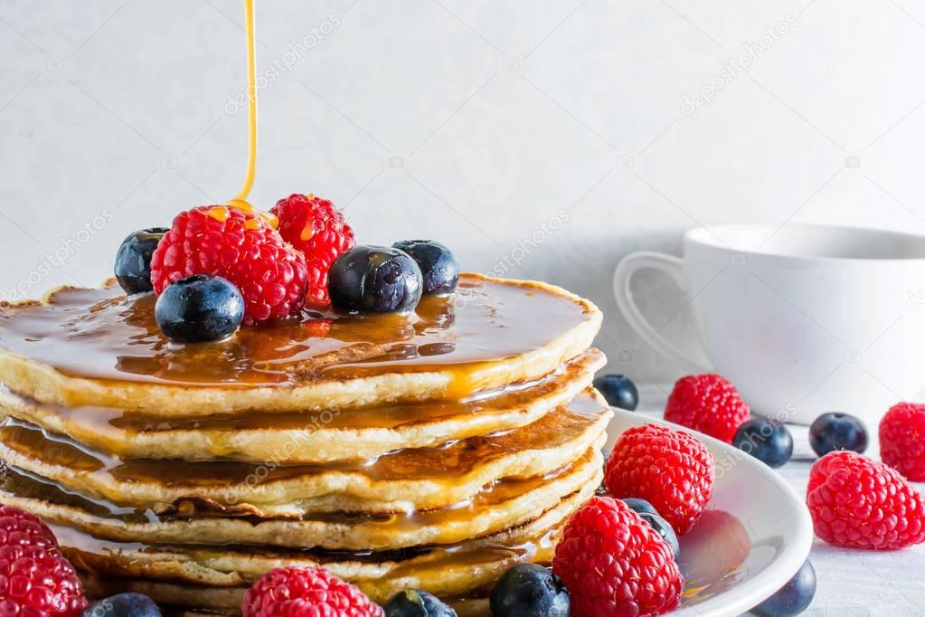 pile of pancakes with fresh berries and caramel sauce