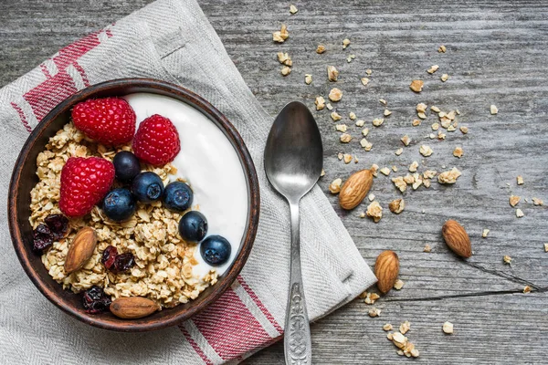 Bowl of oat granola with yogurt, fresh raspberries, blueberries and nuts — Stock Photo, Image