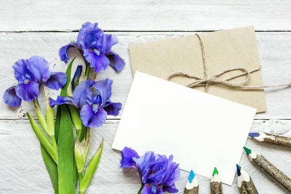 Mavi iris çiçek buketi ve zarf boş beyaz tebrik kartı — Stok fotoğraf