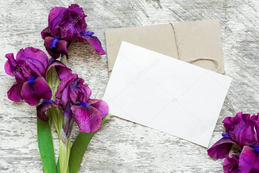 blank white greeting card with purple iris flowers bouquet and envelope