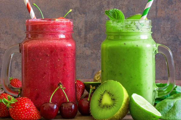 Freshly blended fruit and vegetable smoothies in glass jars on rustic wooden background