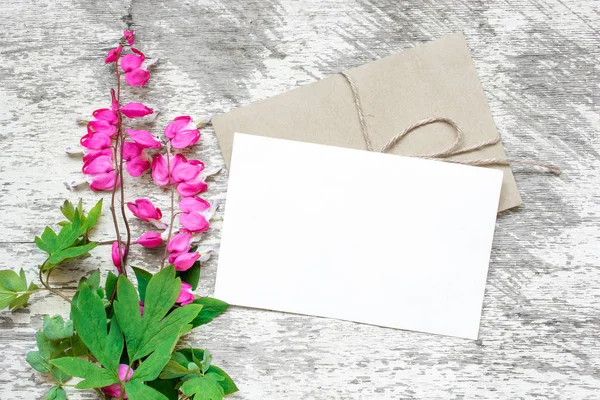 Tarjeta de felicitación blanco en blanco y sobre con ramo de flores silvestres de color rosa — Foto de Stock