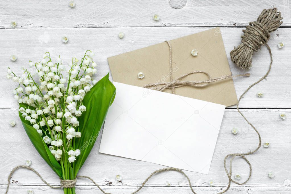 blank white greeting card and envelope with white lily of the valley flowers