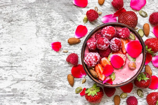 Tazón de batido rosado casero con frambuesas frescas, fresas, nueces, semillas y rosas pétalos de flores — Foto de Stock