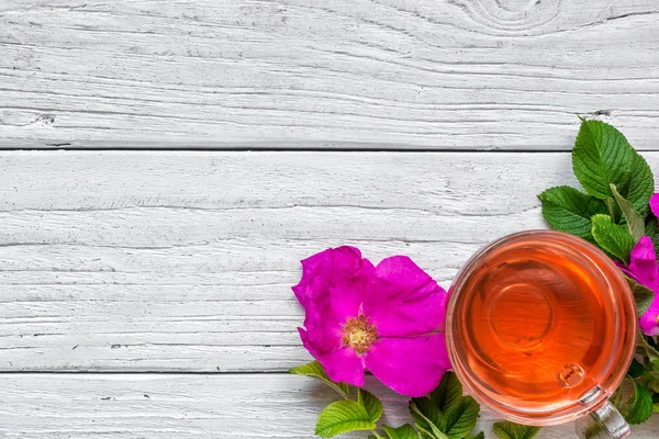 Bitkisel kuşburnu çay beyaz ahşap zemin üzerinde