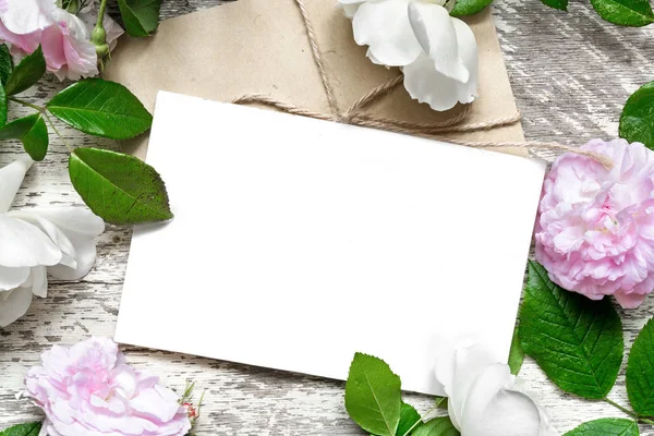 Blank vit gratulationskort och kuvert i ram av rosor blommor — Stockfoto