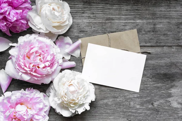 Pustą kartkę z życzeniami lub zaproszenie na ślub i kopertę z przetargu piwonie kwiaty — Zdjęcie stockowe