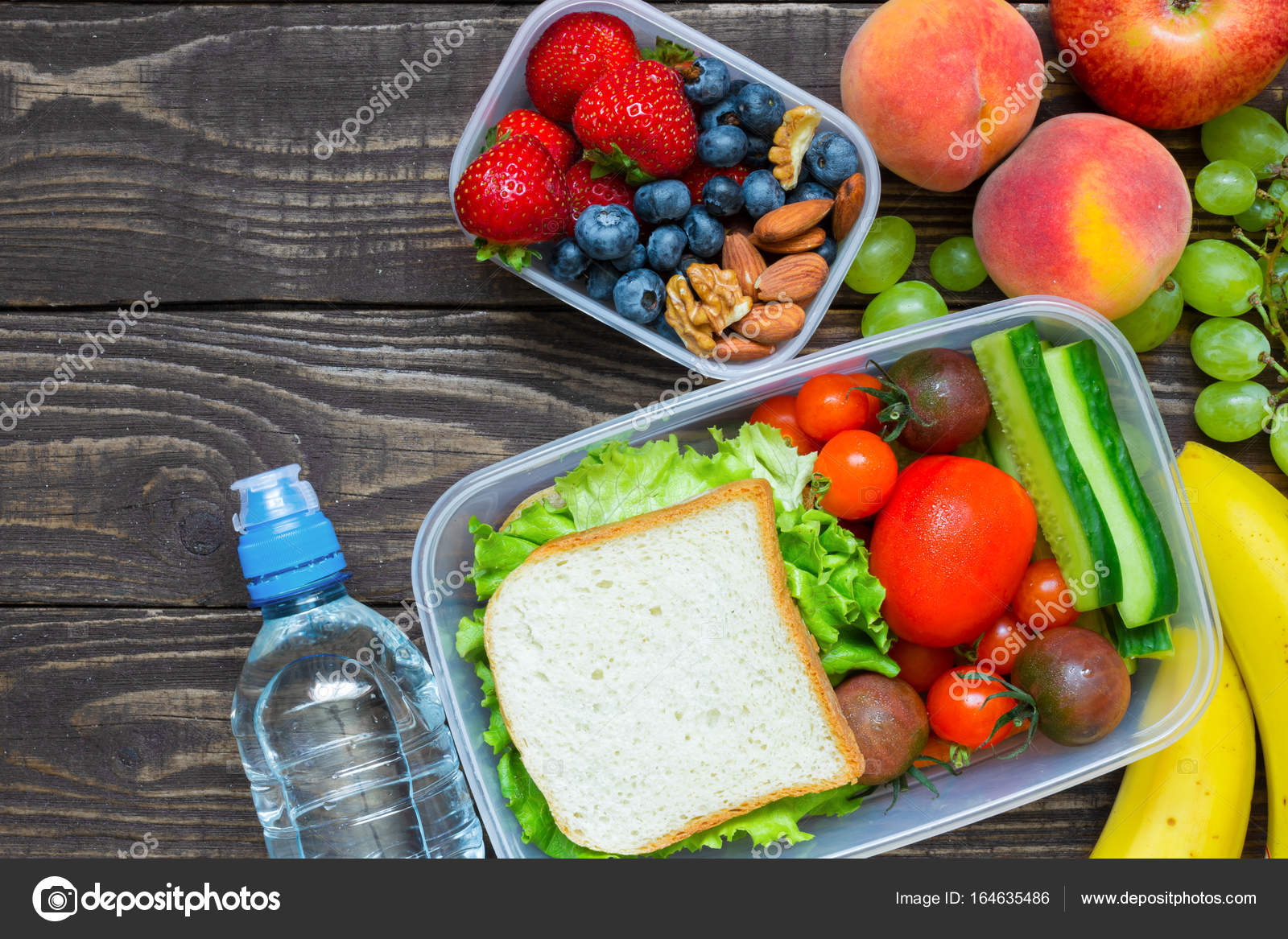 School lunch boxes with sandwich, fruits, vegetables and bottle of