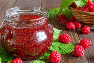 Ahududu reçeli ve rustik ahşap zemin üzerinde bir hasır kase taze ahududu