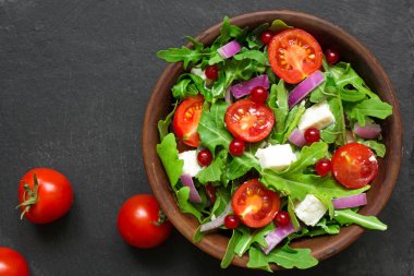 Roka, beyaz peynir, kırmızı soğan ve bir kase içinde kırmızı kuş üzümü ile taze salata