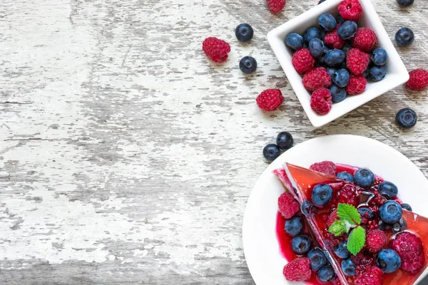 Rebanada de delicioso pastel de queso con frutas de bayas y menta en un plato — Foto de Stock