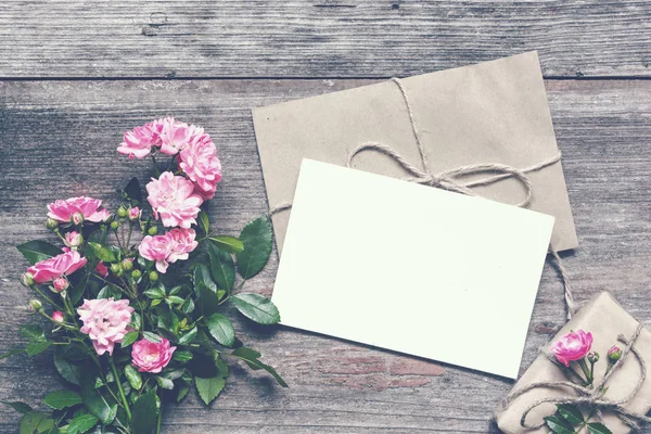 Cartão branco branco branco com rosa rosa flores buquê e envelope com caixa de presente — Fotografia de Stock