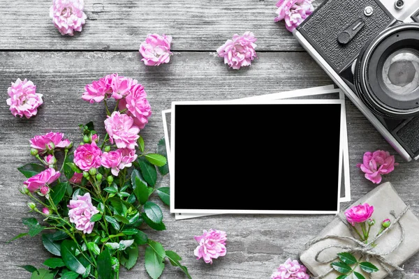 blank photo frame and retro camera with pink rose flowers and gift box.