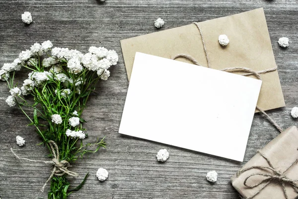Beyaz çiçek buketi ve zarf hediye kutusu ve tomurcukları ile boş beyaz tebrik kartı — Stok fotoğraf