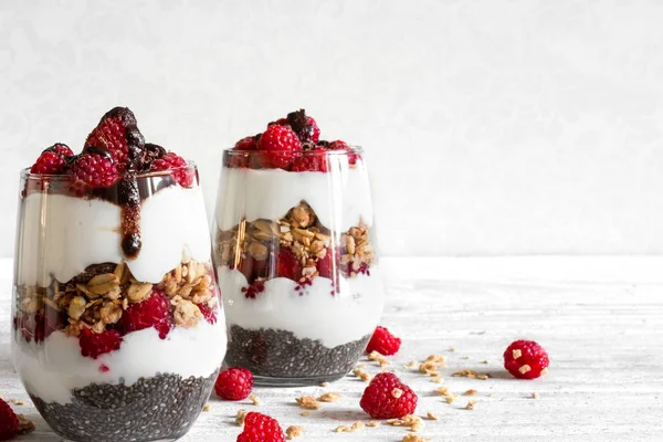 Himbeerjoghurt-Parfait in Gläsern mit Schokolade, Müsli und Chiasamen — Stockfoto