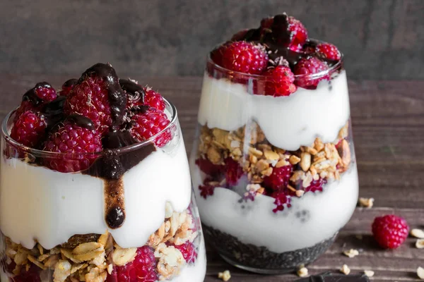 Himbeerjoghurt-Parfait in Gläsern mit Schokolade, Müsli und Chiasamen — Stockfoto