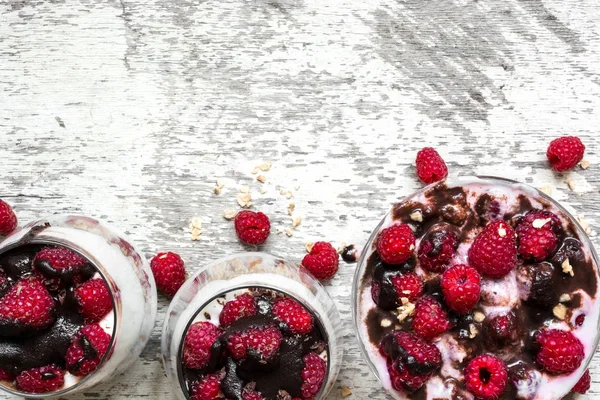 Málnás joghurt desszert a friss bogyós gyümölcsök, a csokoládé és a granola szemüveg — Stock Fotó
