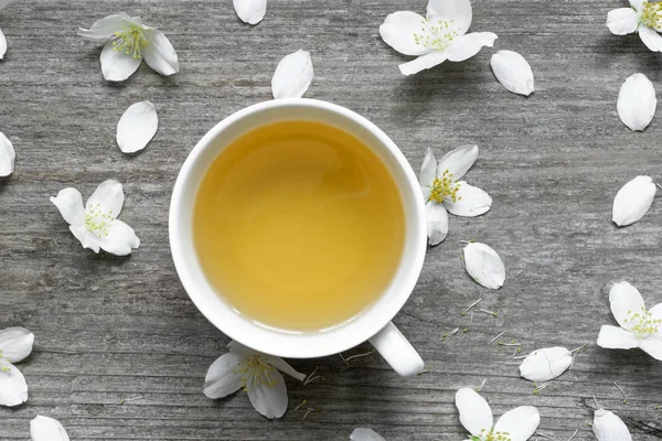 Té de jazmín y flores de jazmín sobre fondo rústico de madera — Foto de Stock