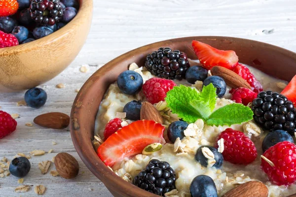 Oatmeal porridge in a bowl with fresh ripe berries and mint — Stock Photo, Image