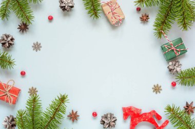 Çam dalları, kırmızı meyveler, hediye kutuları, retro oyuncak ve çam kozalakları Noel çerçeve yapılmış