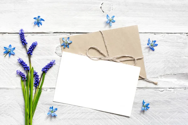 空白的白色问候卡片和信封与春天蓝色花花束和芽 — 图库照片