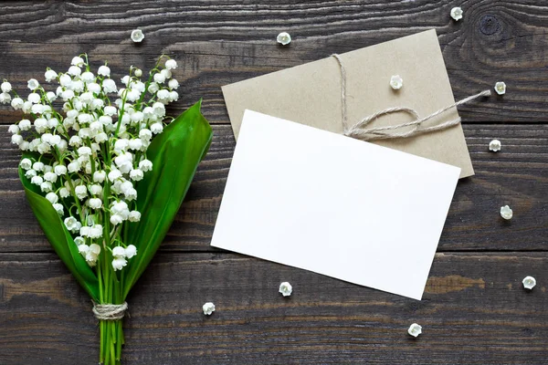 Blank vit gratulationskort och kuvert med våren liljekonvalj blommor och knoppar — Stockfoto