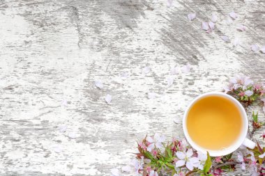 yaprakları ile beyaz rustik ahşap tabloda çay ve bahar kiraz çiçeği veya sakura çiçekler