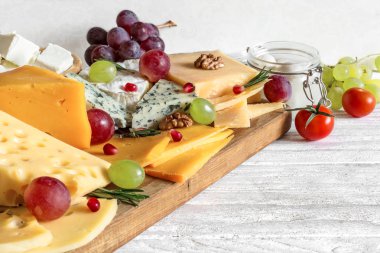 Peynir çeşitli tür ahşap kesme tahtası kiraz üzüm, nar, biberiye ve domates ile servis