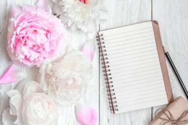 pembe ve beyaz Şakayık çiçekleri beyaz tahta masada boş çizgili defter ve hediye kutusu