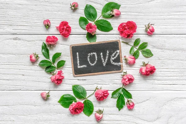 Composición de flores. marco hecho de flores rosadas con inscripción de amor en pizarra — Foto de Stock