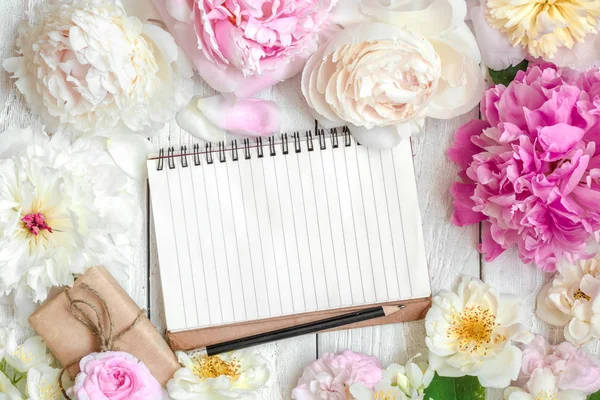 Blank lined notebook in flower frame made of pink and white peony, roses and jasmine flowers and gift box — Stock Photo, Image