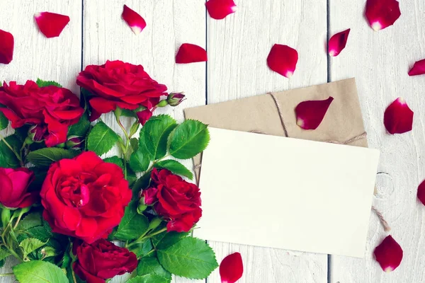 Carte de vœux vierge et enveloppe avec fleurs et pétales de roses rouges — Photo