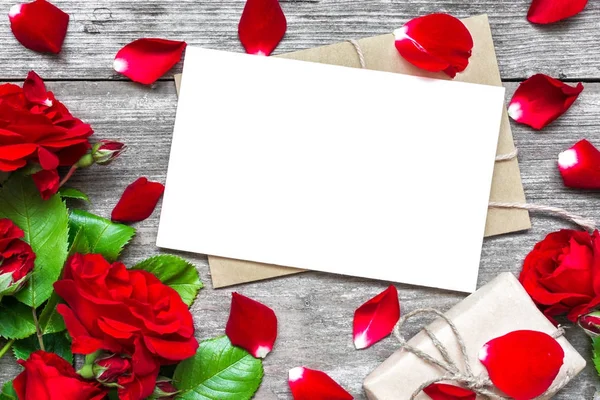 Blank vit gratulationskort med röd ros blommor bukett och kuvertet med kronblad och presentbox — Stockfoto