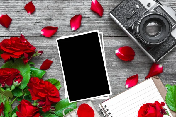 Vintage retro kamera ve kırmızı gül çiçekler buket ve çizgili defter ile boş fotoğraf çerçevesi — Stok fotoğraf