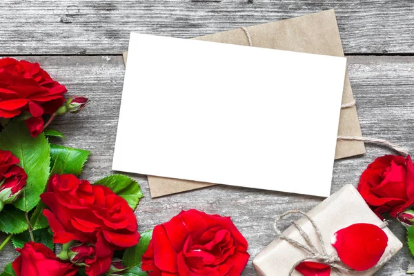 Blank vit gratulationskort med röd ros blommor bukett och kuvertet med presentask — Stockfoto