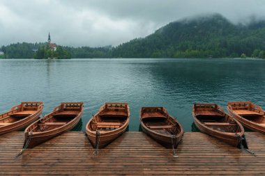 Bled Gölü, ada, kale, tekneler ve arka plan dağlarda sisli ve yağışlı gün, Slovenya