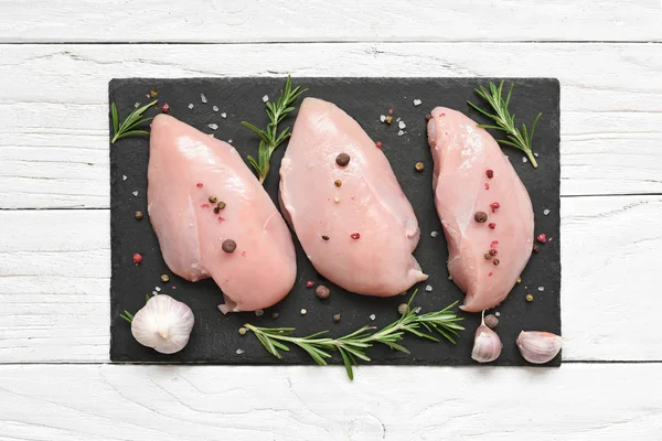 Pechugas de pollo crudas con romero y especias en pizarra negra —  Fotos de Stock