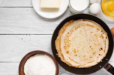 Beyaz masada malzemelerle tava üzerinde krep yığını