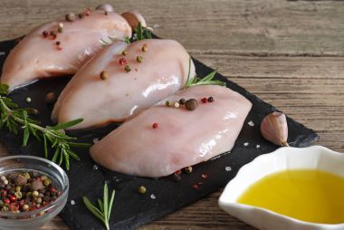 Çiğ tavuk göğsü witn biberiye, zeytin yağı ve siyah arduvaz kesme tahtası üzerinde baharat