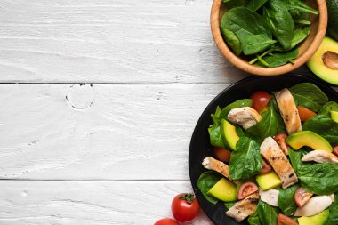 siyah plat içinde kiraz domates, ıspanak, tavuk ve Avokado salatası