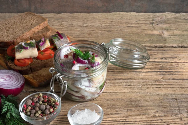 tuz, biber, otlar ve sandviç kahvaltı için bir kavanoza soğan ile salamura ringa balığı