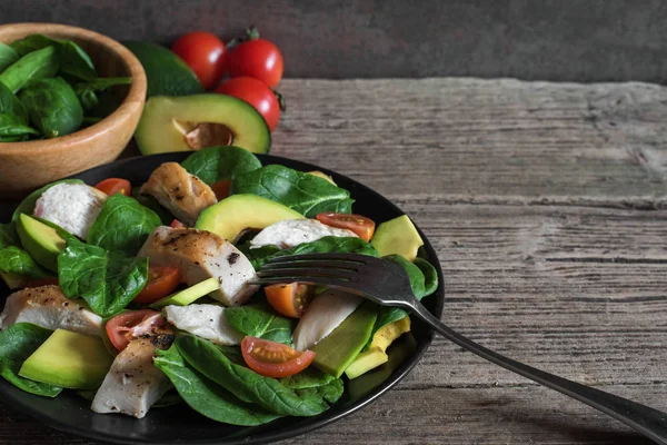 çatal ile siyah plaka kiraz domates, ıspanak, tavuk ve Avokado salatası.