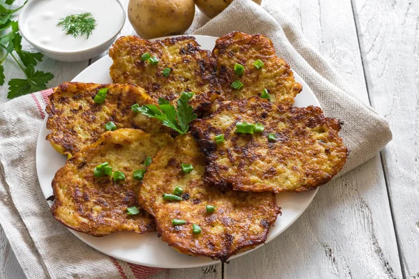 Panquecas caseiras de batata com creme azedo na mesa de madeira rústica — Fotografia de Stock