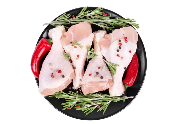 Patas de pollo crudas con romero y chile sobre un plato negro aislado sobre fondo blanco —  Fotos de Stock